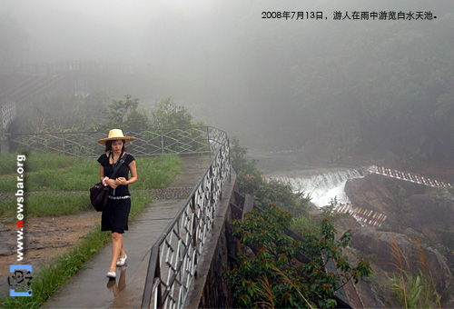 2008年7月13日，广东增城白水寨风景名胜区，一名游客在雨中游览白水天池。